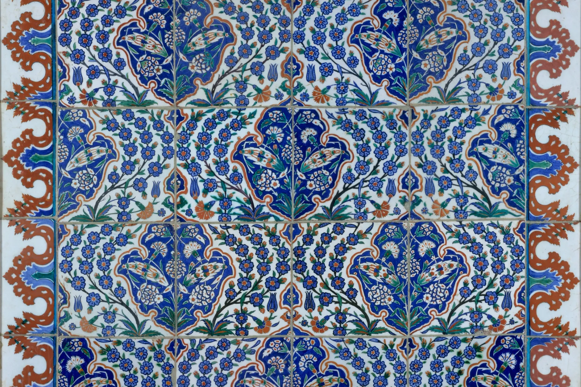 Iznik tile panel of blue flowers and saz leaves on white, edged with a scalloped red border