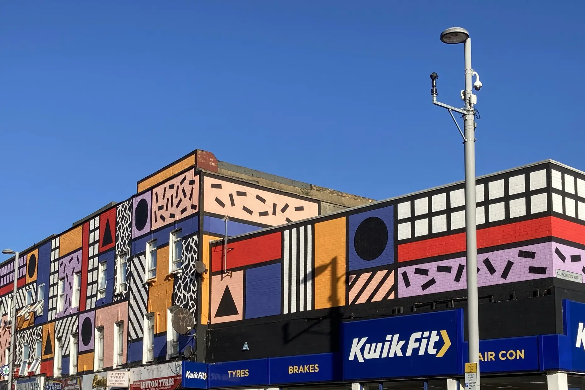 Building facade painted with Memphis style geometric shapes and clashing colours by Camille Walala