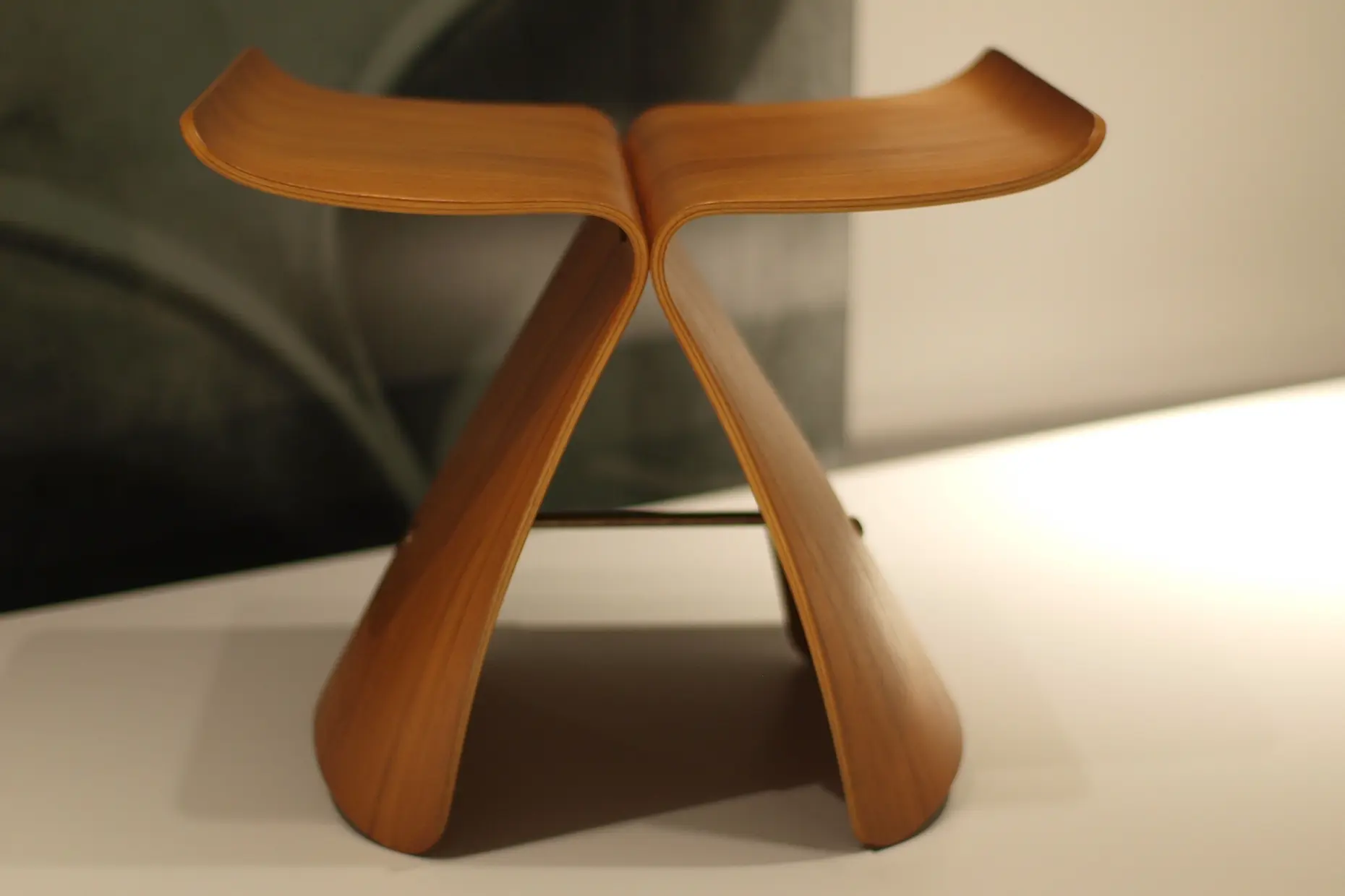 Butterfly Stool with two curved plywood halves meeting at a slender steel stretcher