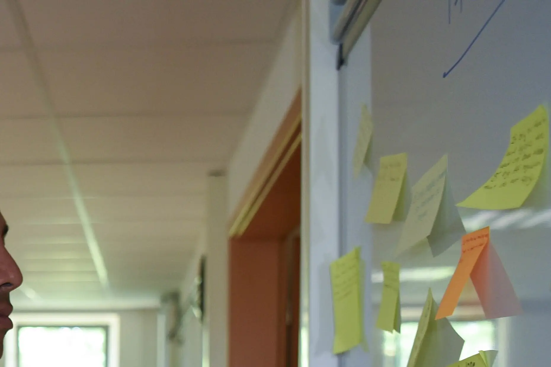 Sticky notes on a workshop wall, handwritten ideas grouped and re-stuck during a session