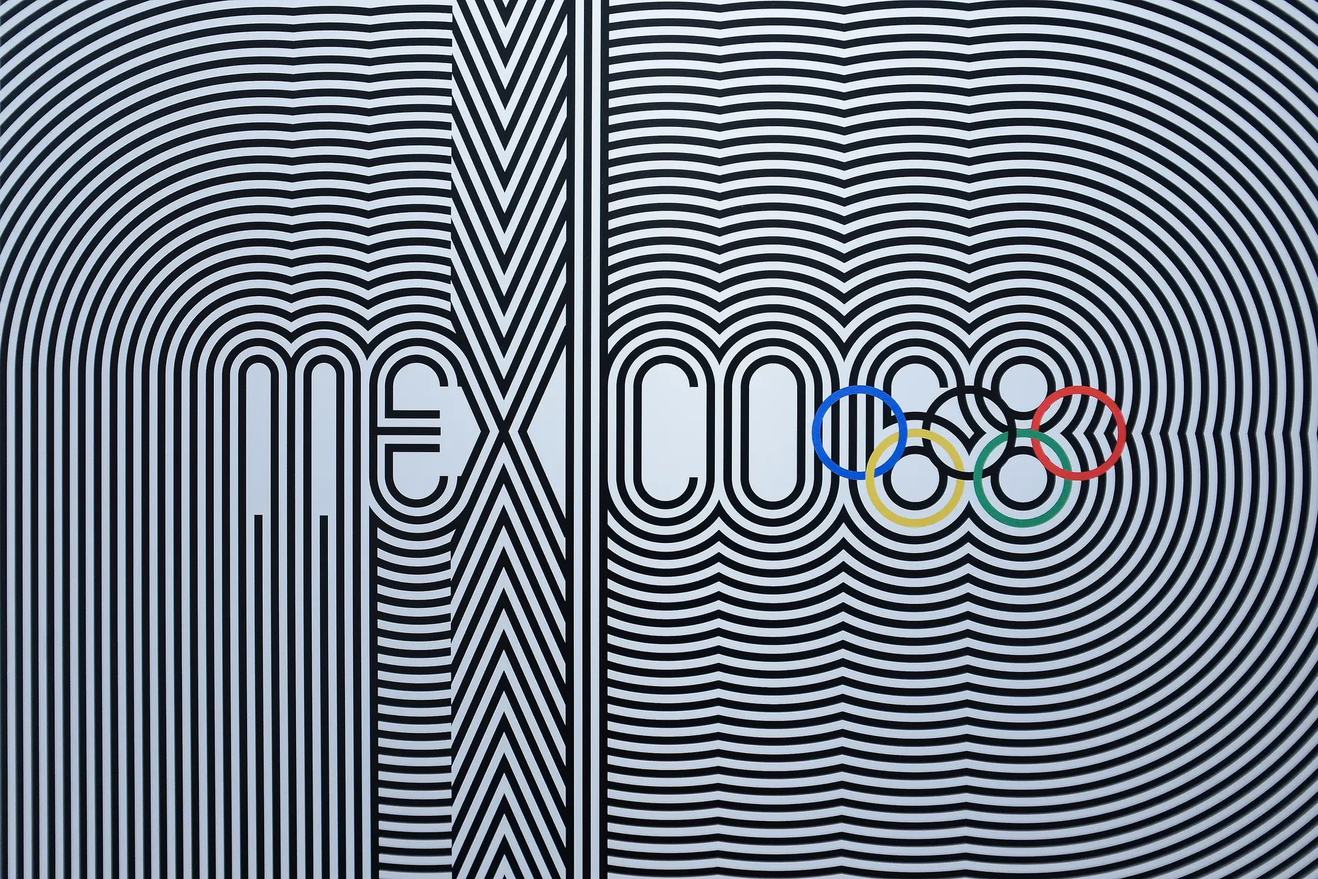 Lance Wyman's Mexico 68 logo in black and white concentric lines radiating from the letters, with the Olympic rings in colour