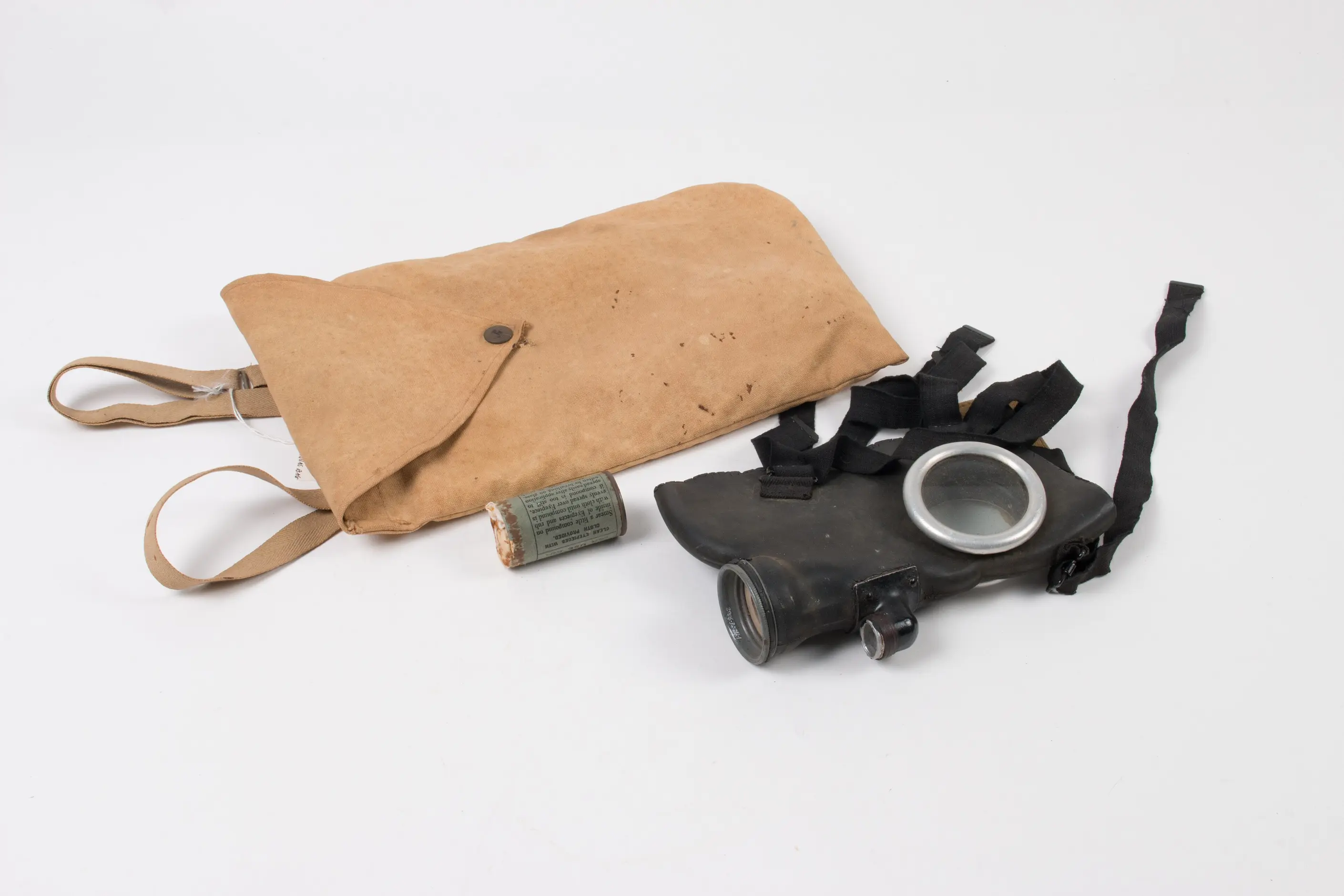 A canvas gas mask bag beside a rubber gas mask with straps and a round eyepiece