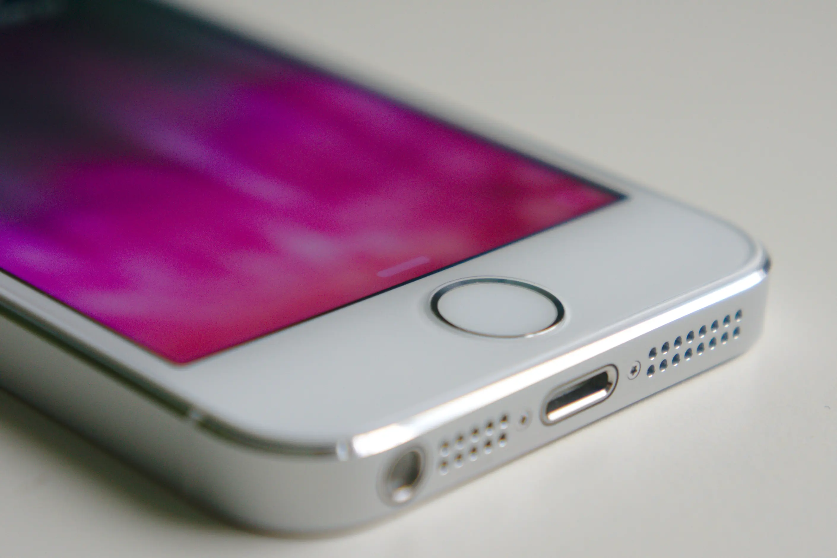Close up of a silver iPhone's round home button and Lightning port edge