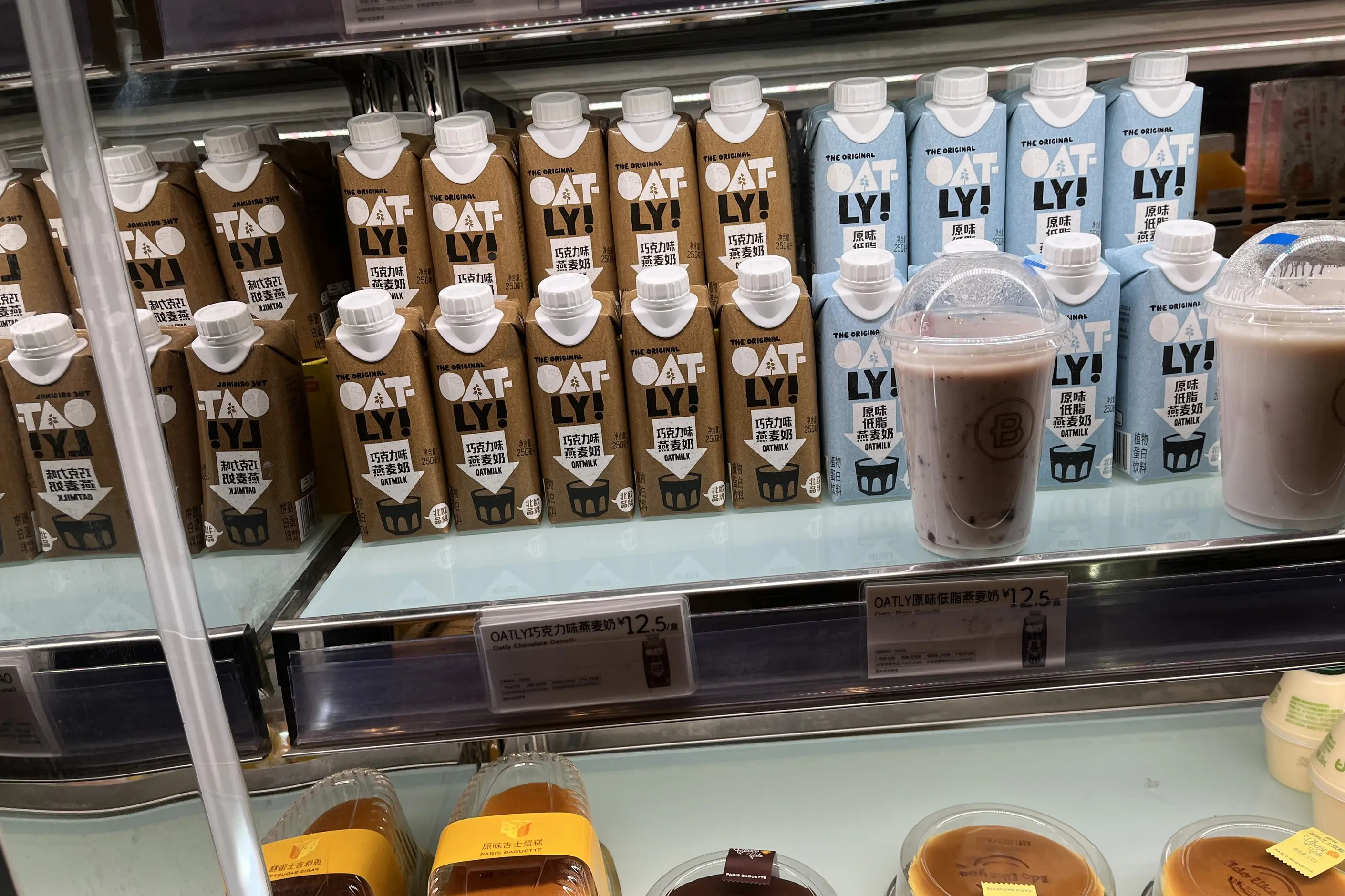 Shelf of Oatly oat milk cartons with their bold hand lettered Oat-ly wordmark
