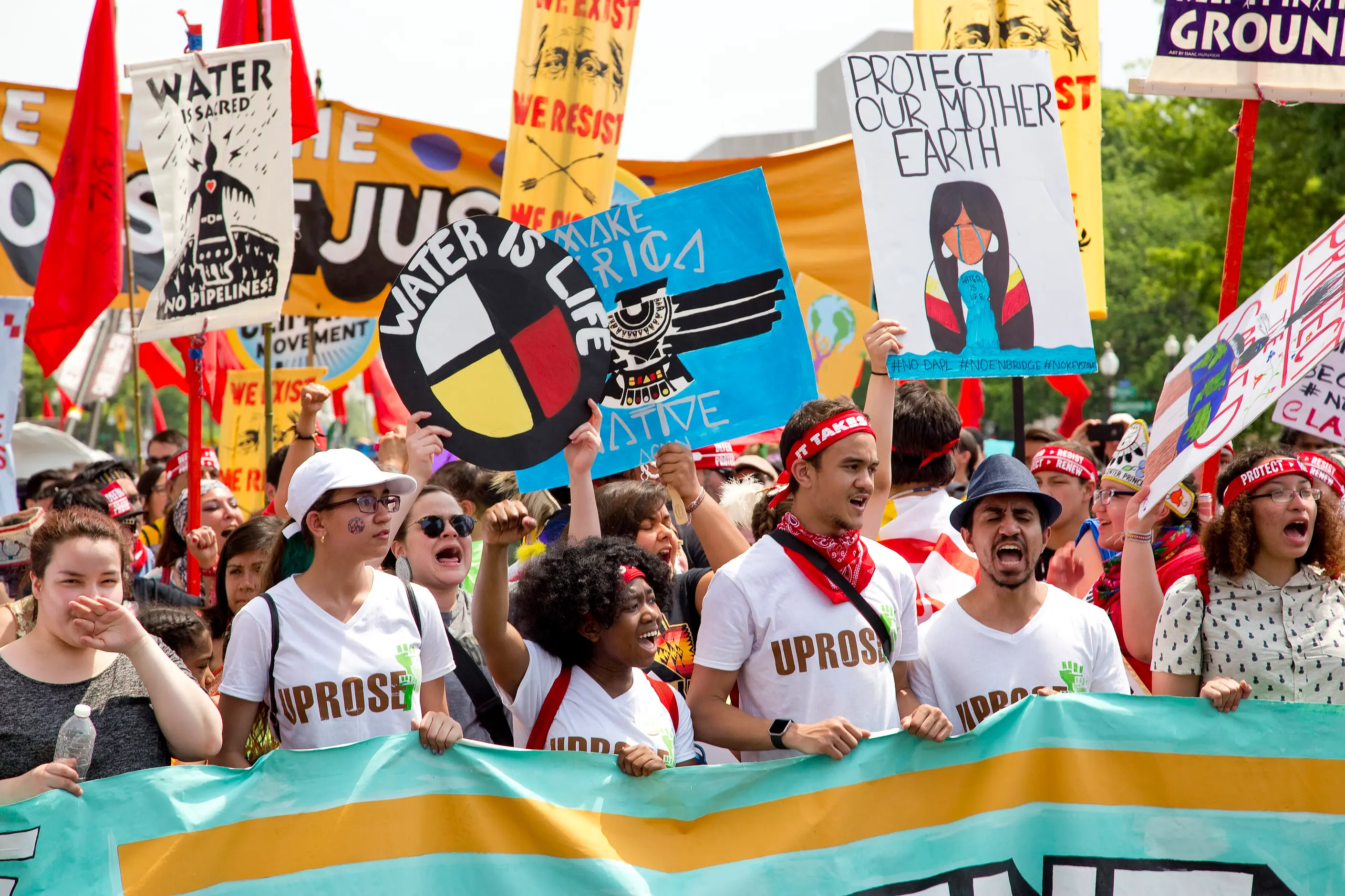 Climate marchers behind a banner, placards reading Water is life and Protect our Mother Earth