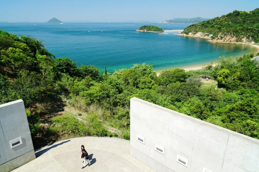 Two bare concrete walls with punched square windows overlooking a bay, part of Tadao Ando's building