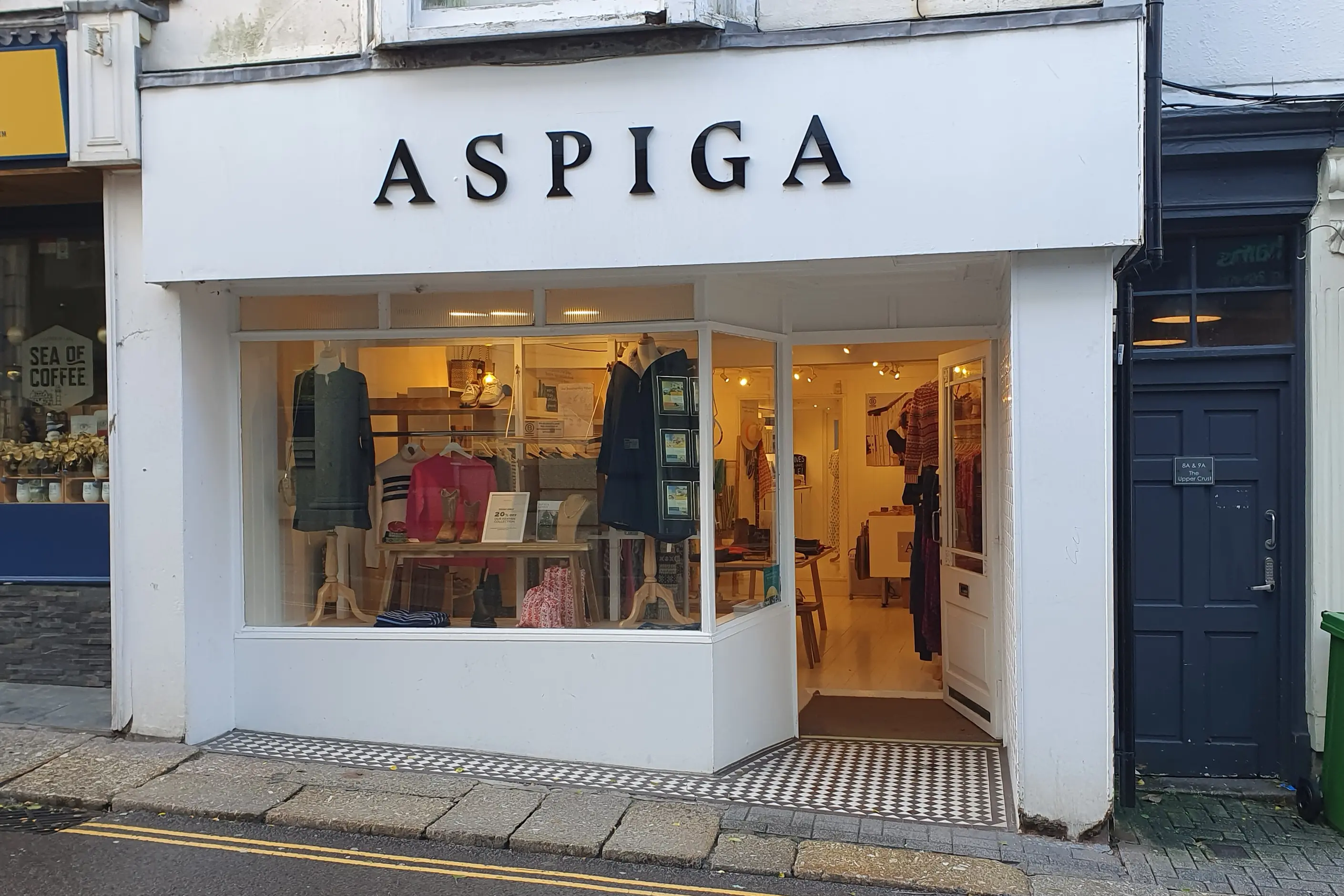 A clothing shop's own branded storefront with lit window displays