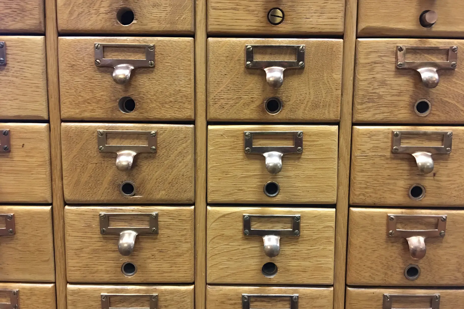 Rows of oak card catalogue drawers with brass label holders and pull handles