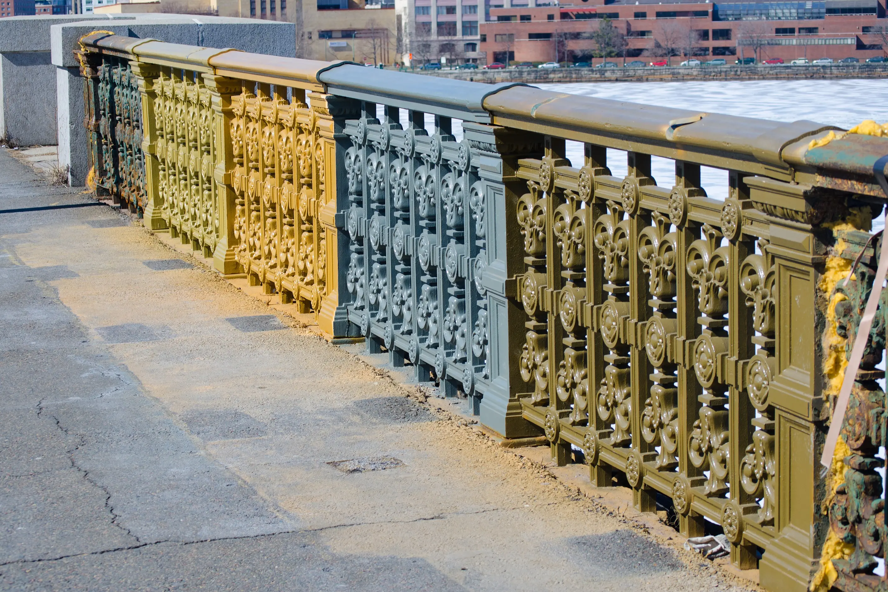 Bridge railings painted in test sections of yellow, blue-grey and olive to compare colours on the real object