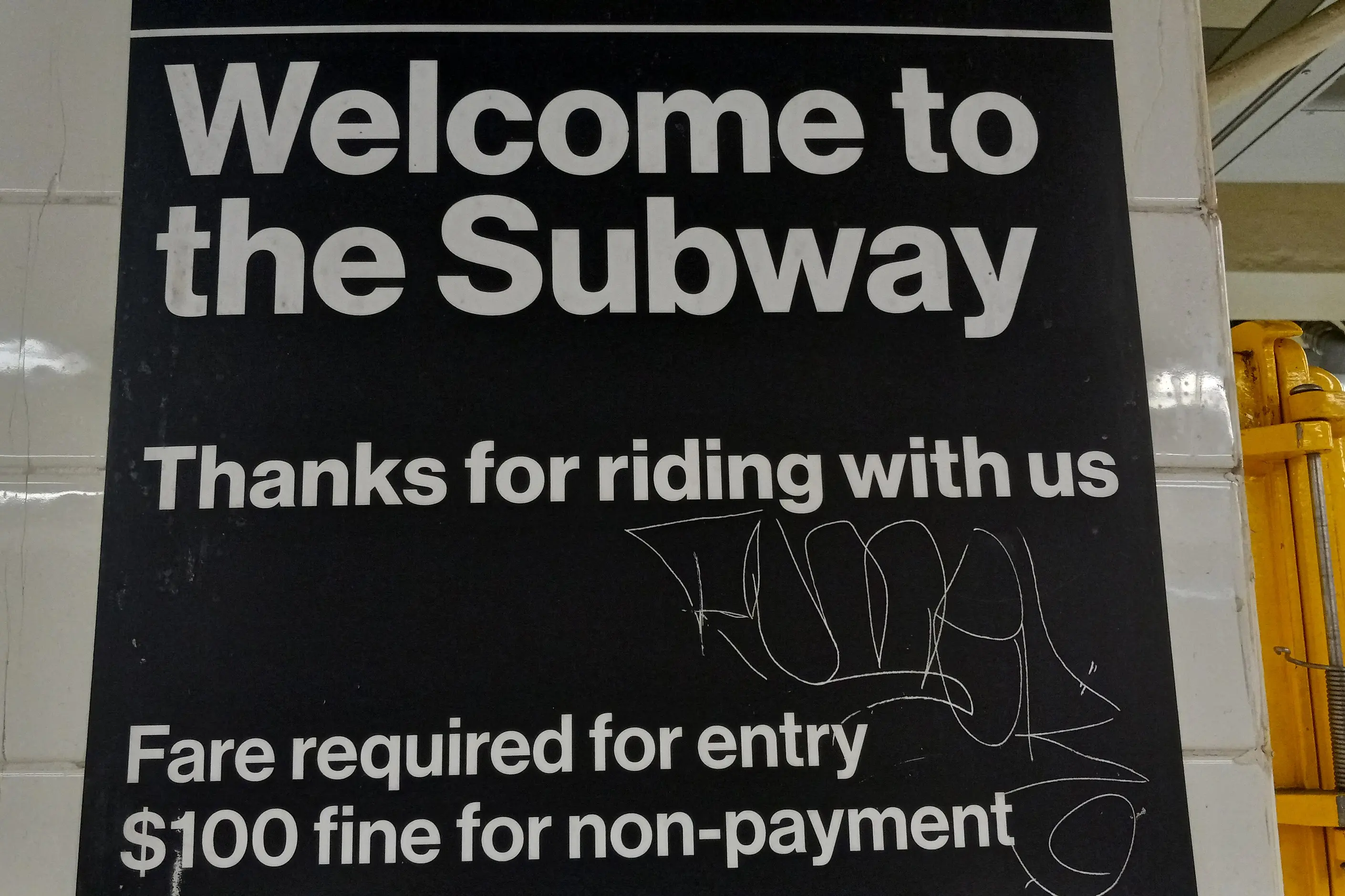 A black New York subway sign reading Welcome to the Subway in white Helvetica, with fare notices below