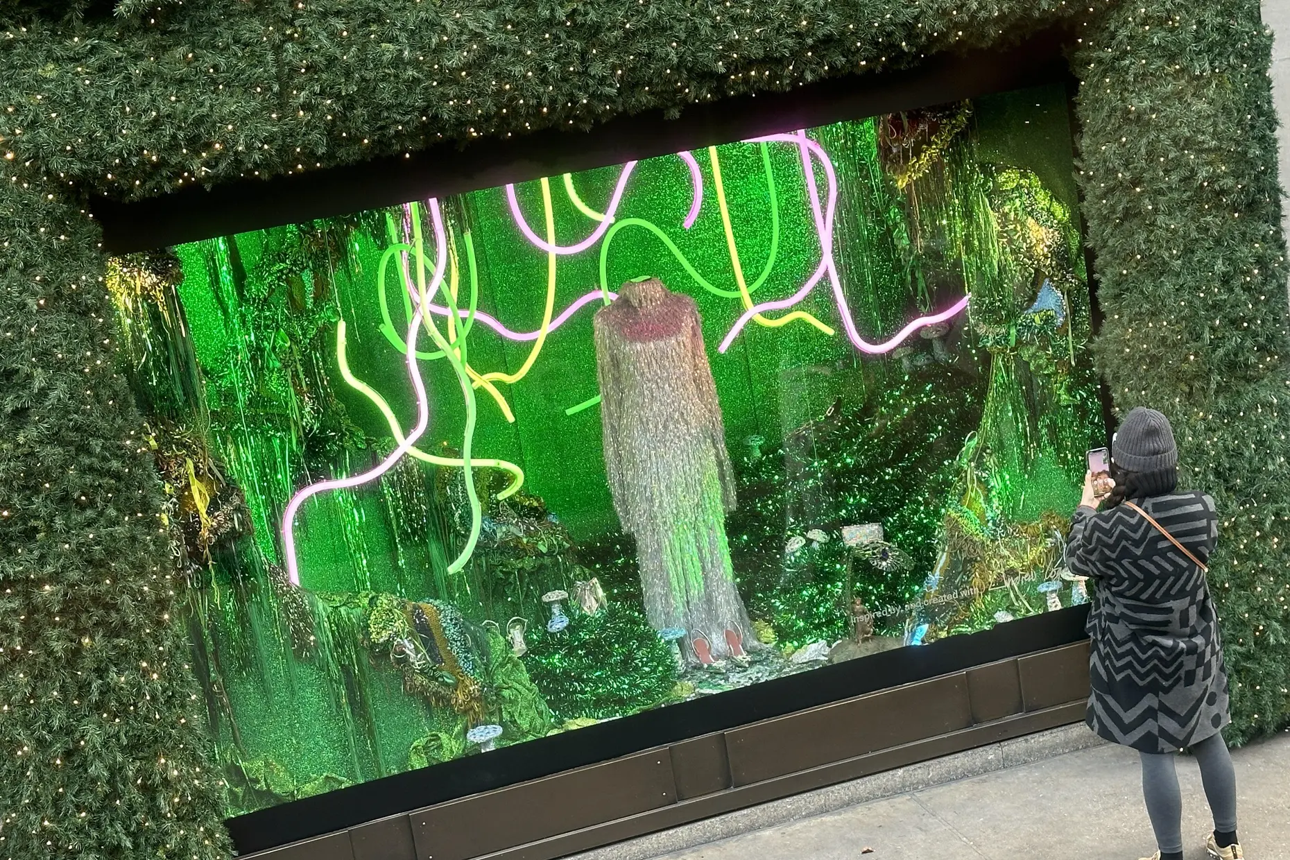 Glittering green maximalist department store window with neon tendrils and a shaggy costume figure