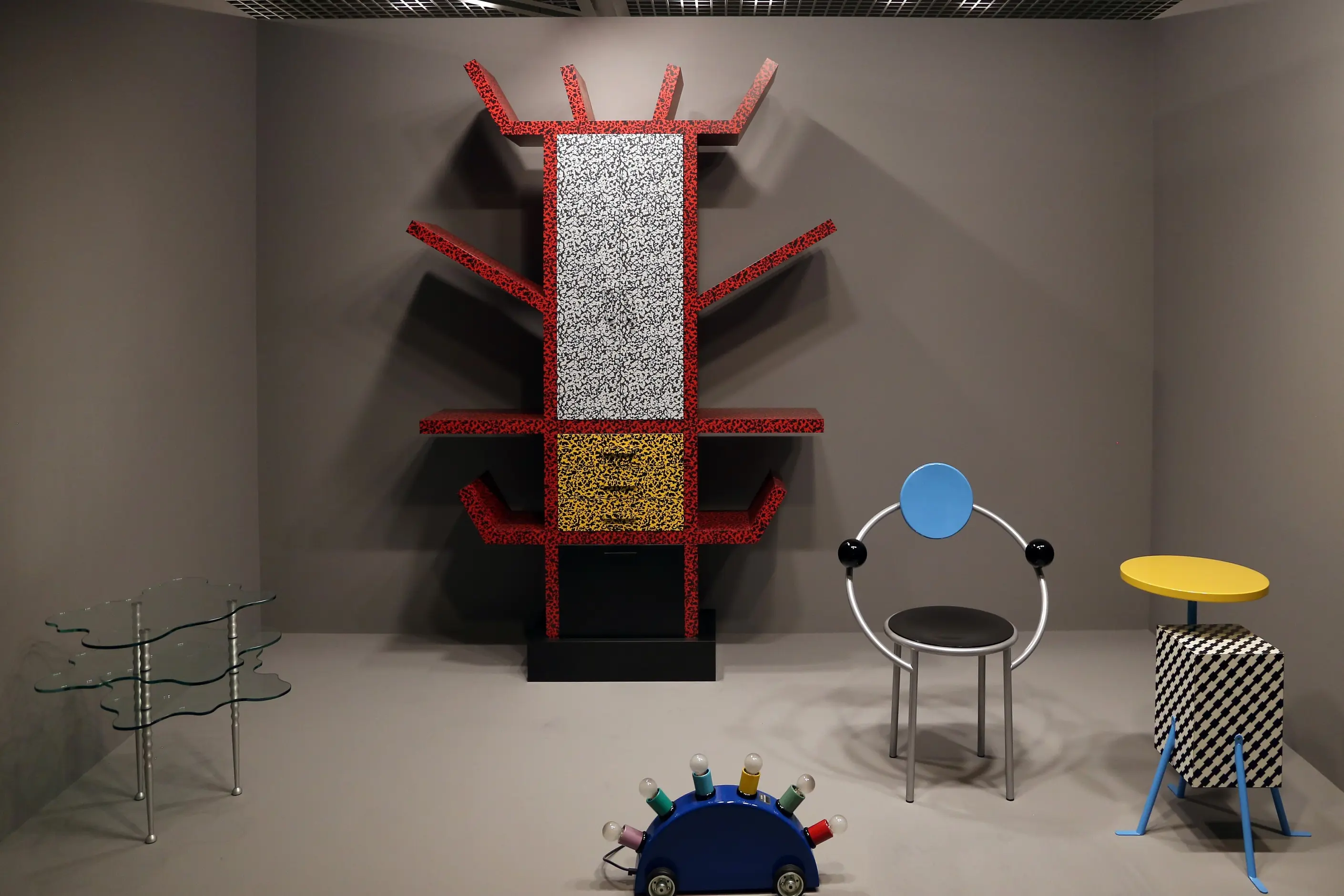Sottsass Carlton Bookcase in red terrazzo laminate beside other Memphis Group furniture