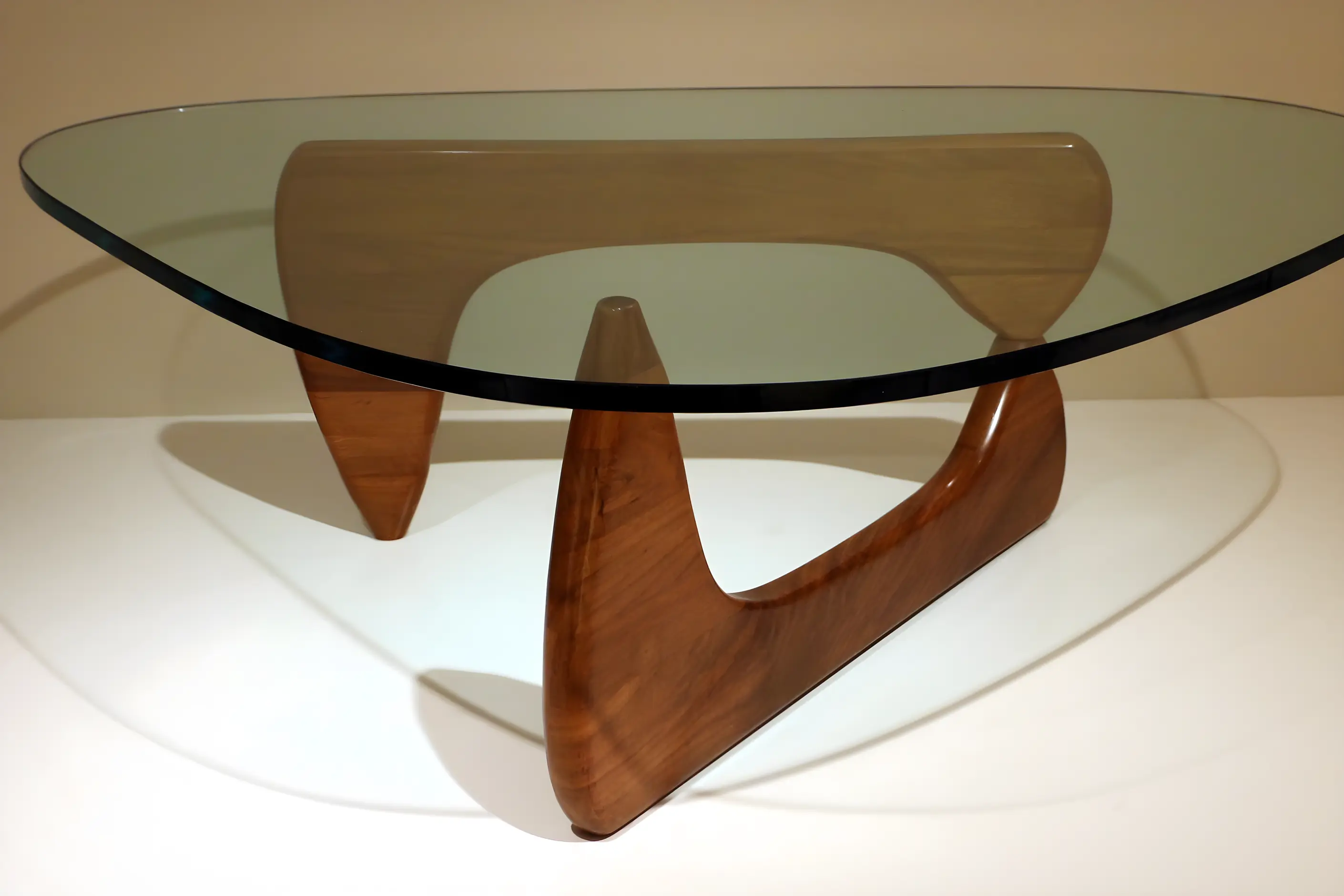 Noguchi coffee table with a glass top resting on two interlocking asymmetric wooden bases