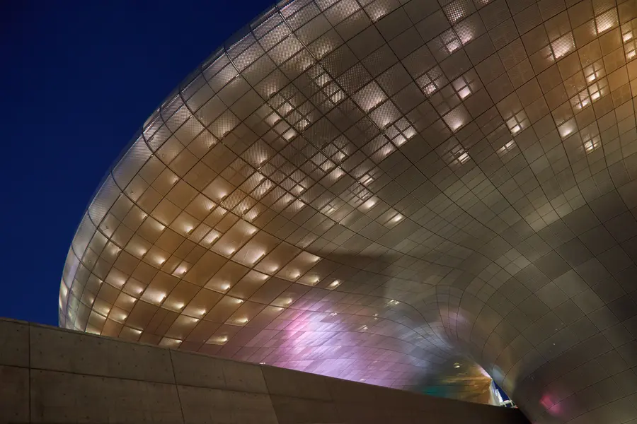 Dongdaemun Design Plaza's curved perforated metal facade lit up at night