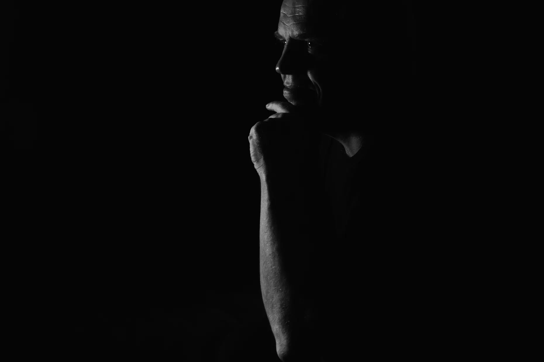 Contemporary black and white portrait of a man lit by one hard directional light against black