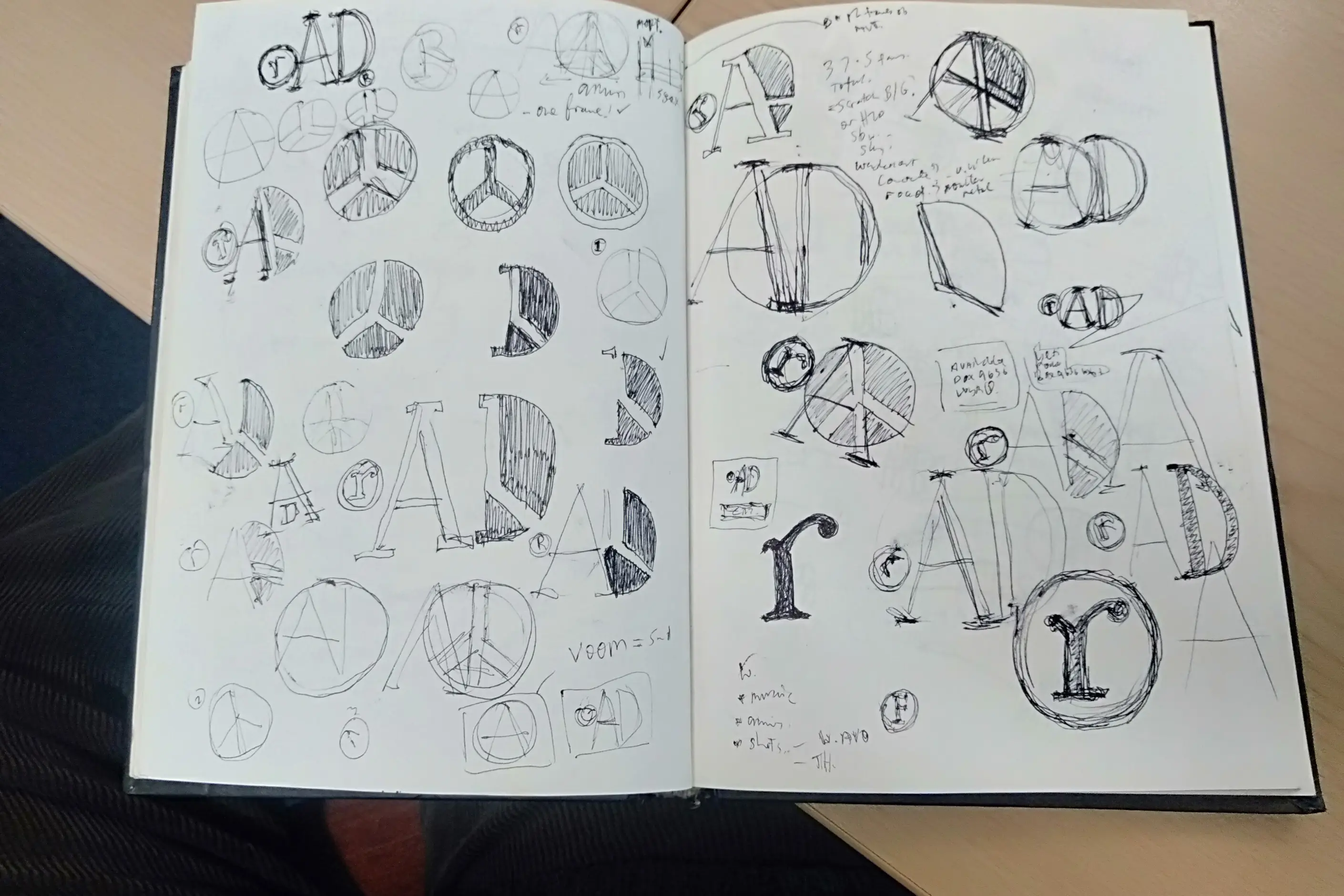 An open sketchbook filled with dozens of pencil logo explorations of the letters A, D and r