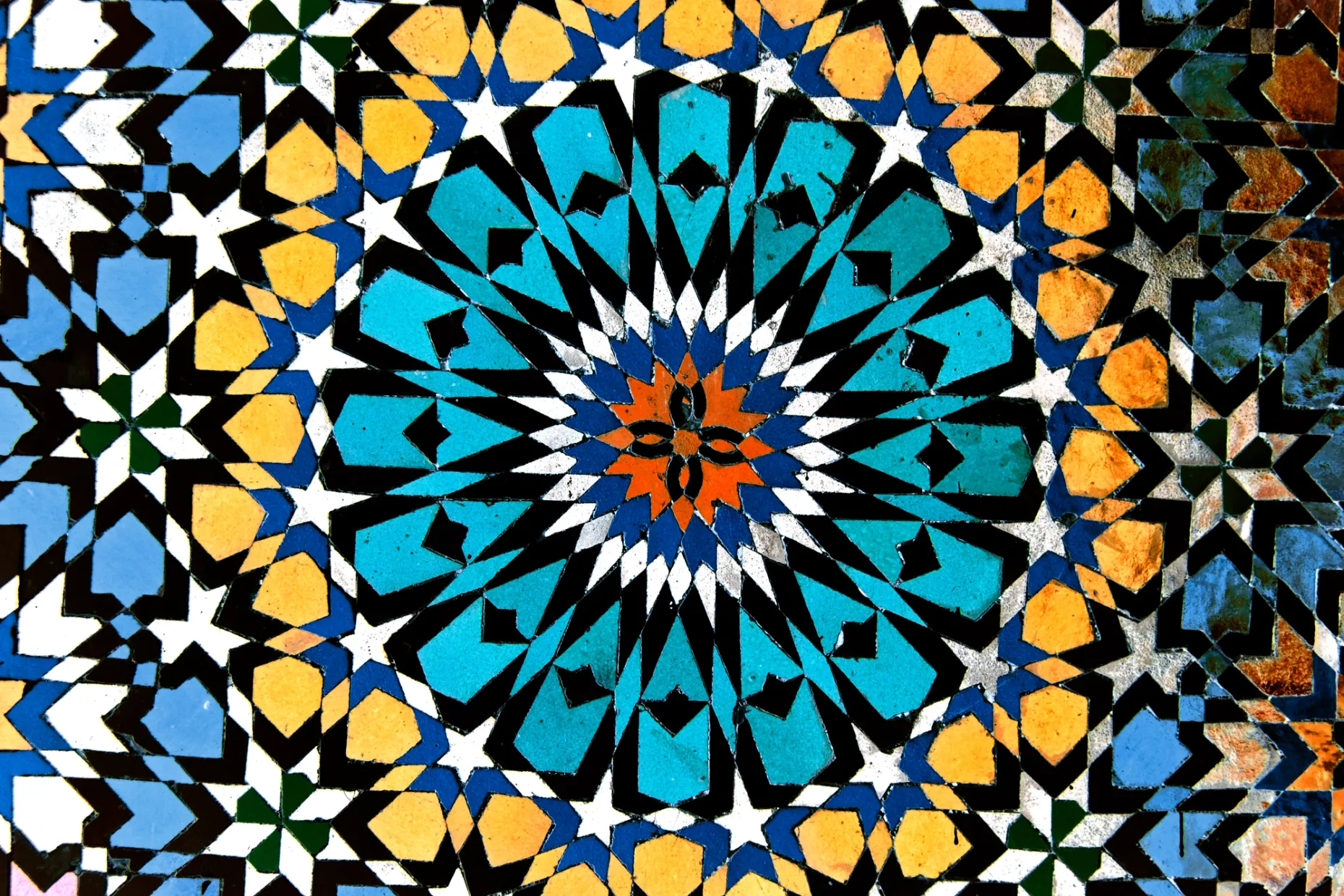 Moroccan zellige of hand-cut glazed pieces in blue, black, white and ochre radiating from a central star