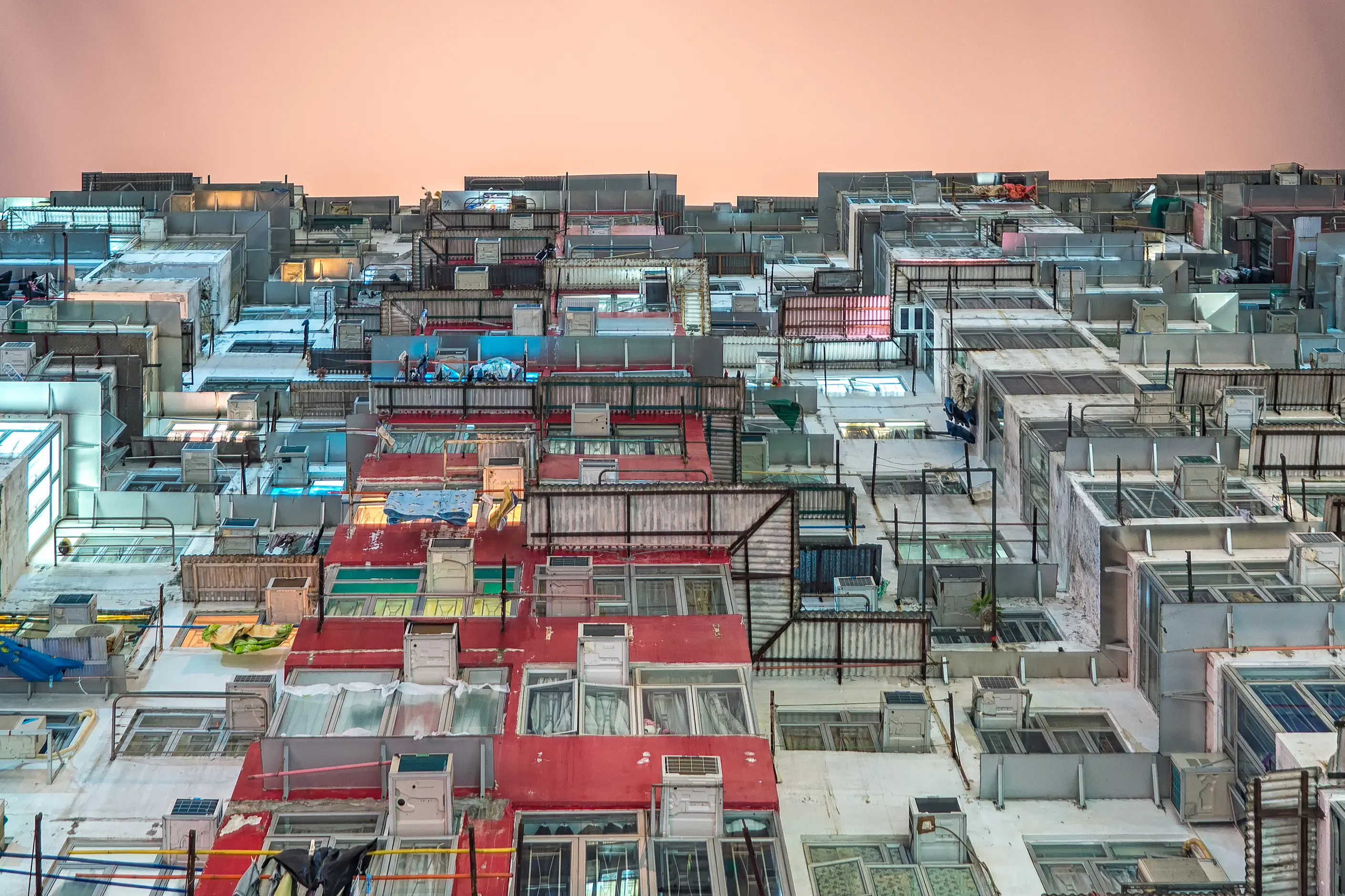 Looking up at a dense Hong Kong housing block, hundreds of window modules and air conditioners stacked in a rigid grid