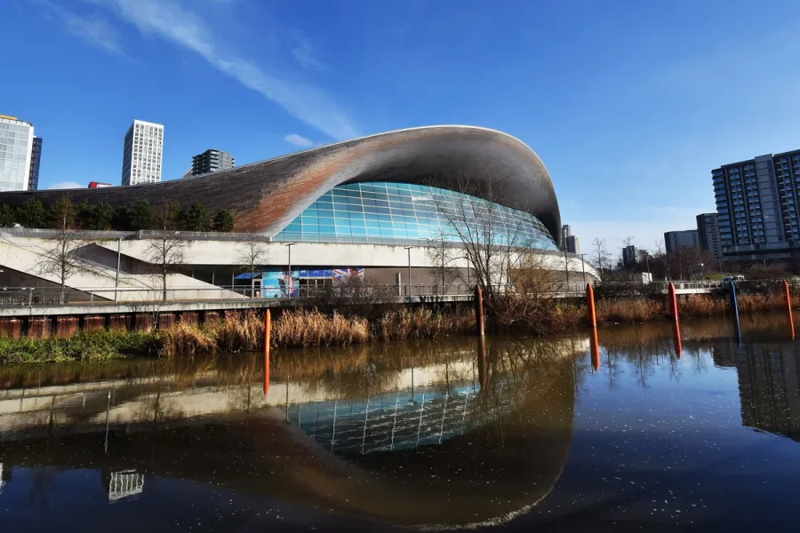 London Aquatics Centre's sweeping curved roof reflected in the water beside it