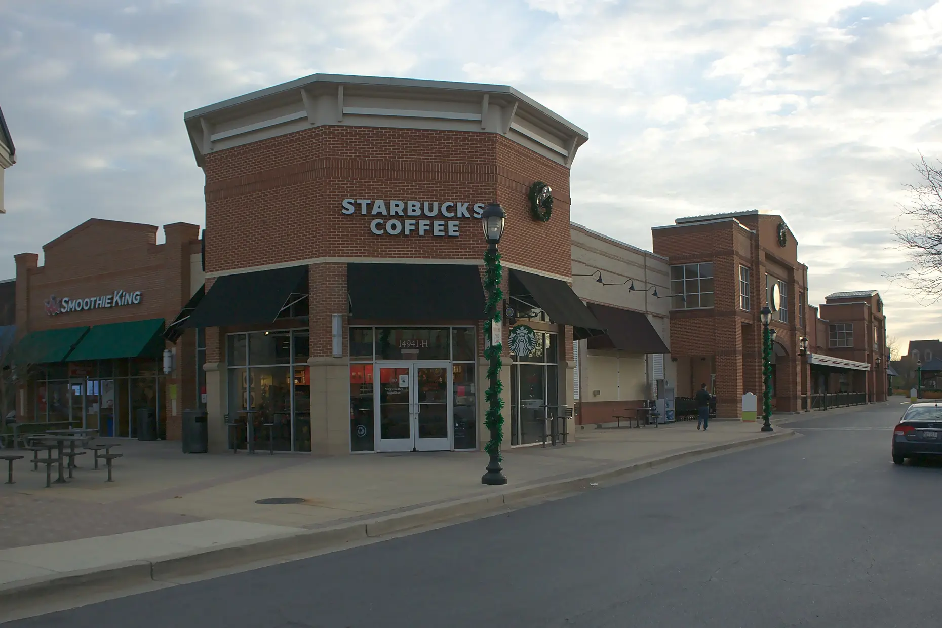 A branded Starbucks coffee shop storefront on a suburban street corner, the chain's combined cafe and social space.
